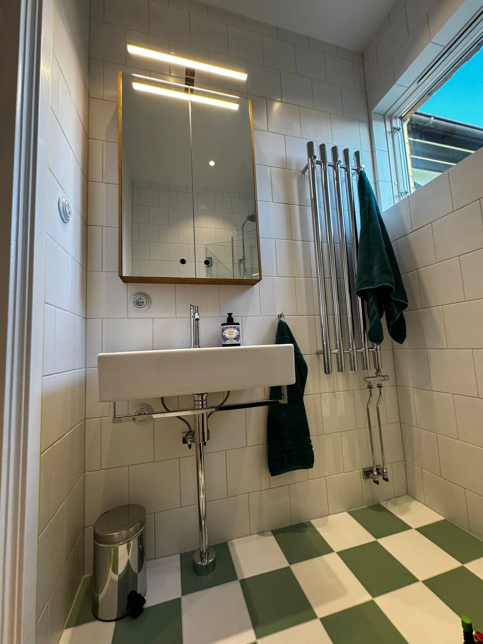 Svart handdukstork ansluten till husets värmekrets, monterad på mörkt klinker i Falsterbo.